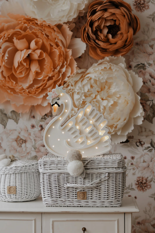Decorative swan lamp with wicker baskets and floral wall backdrop