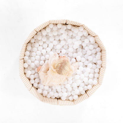Child playing in a ball pit filled with white balls on a white background