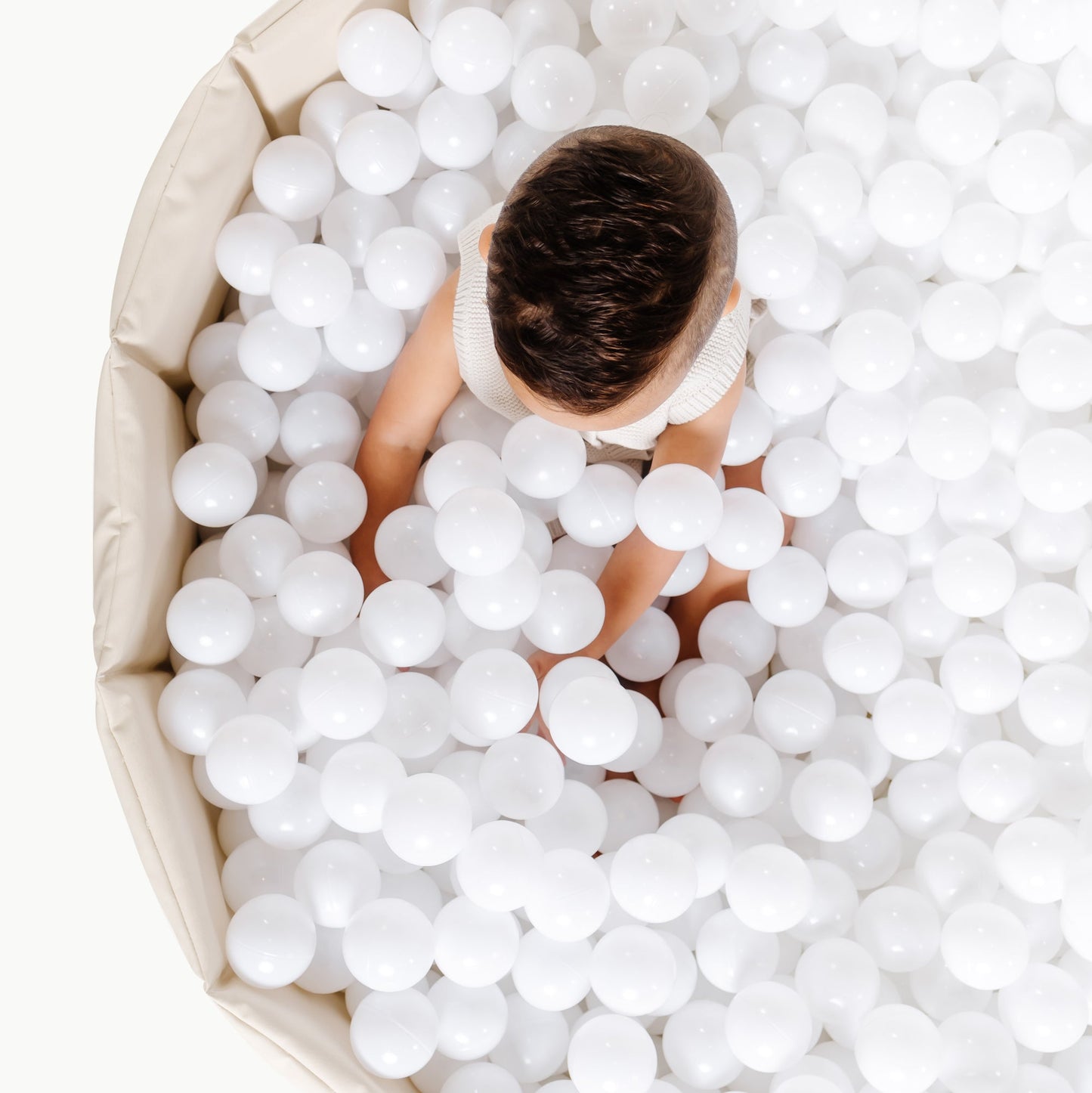 Child playing in a ball pit filled with white balls