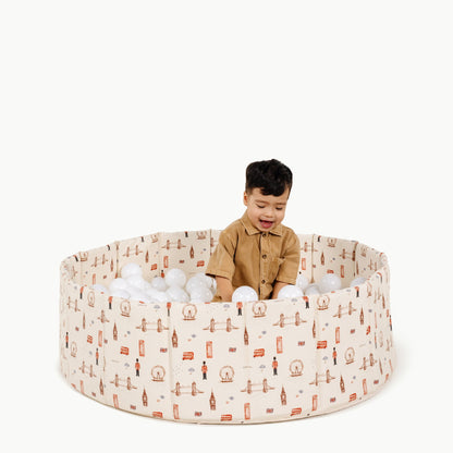 Child playing inside a patterned playpen with white balls on a white background