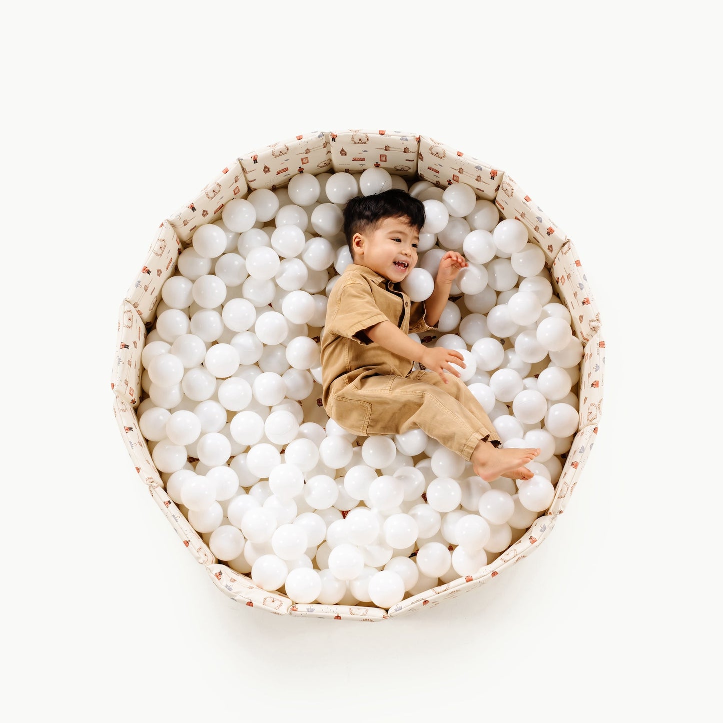 Child playing with white balls in a large bowl on a white background