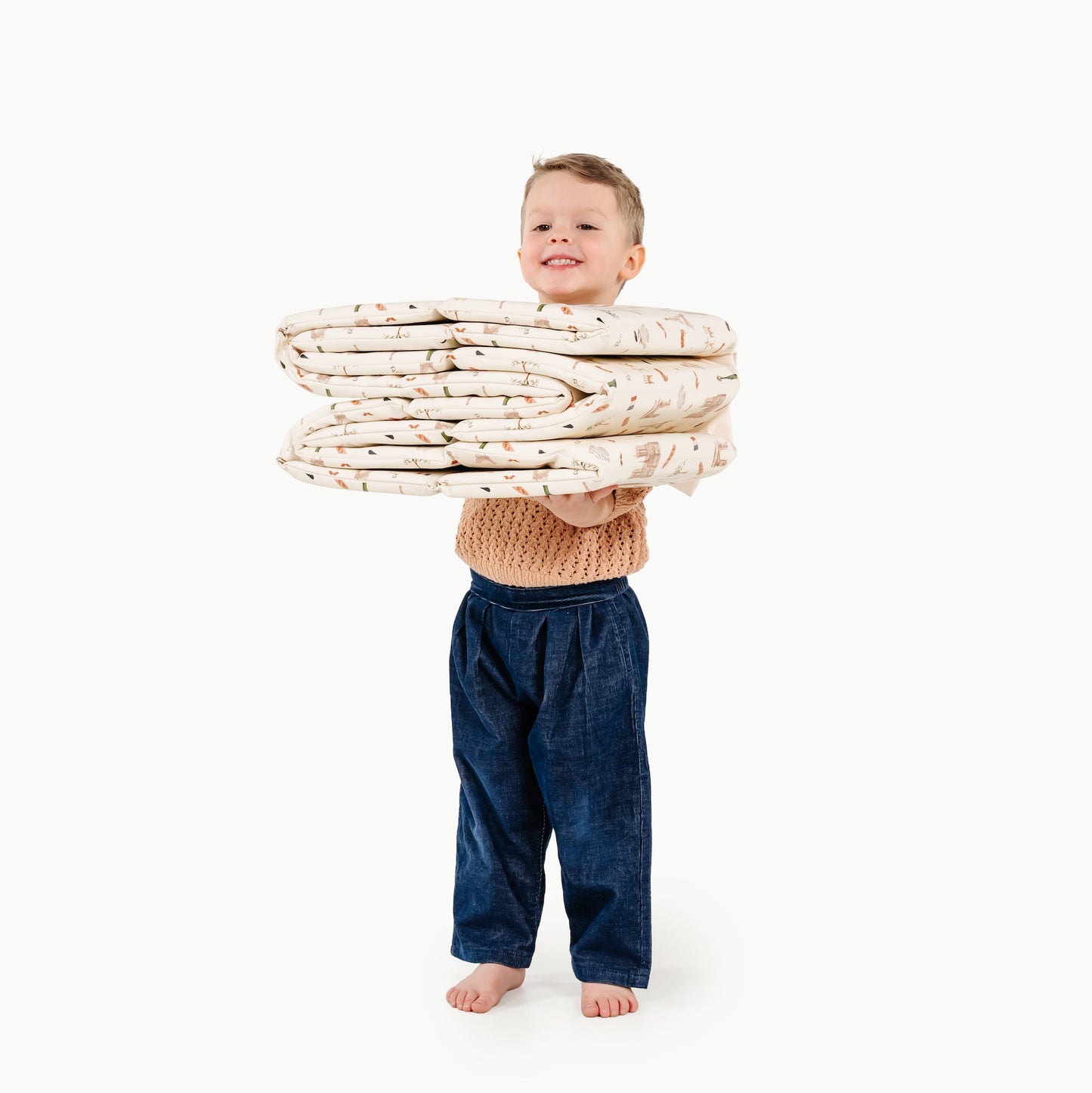 Child holding a stack of folded blankets on a white background