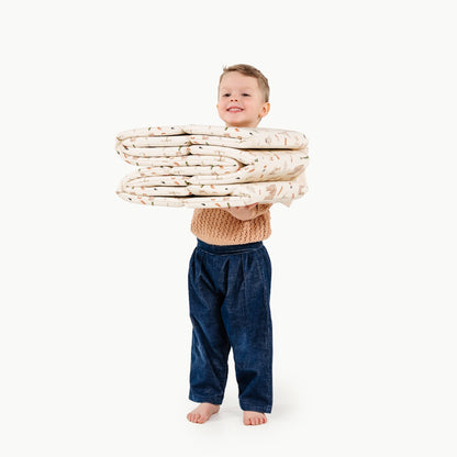 Child holding a stack of folded blankets on a white background