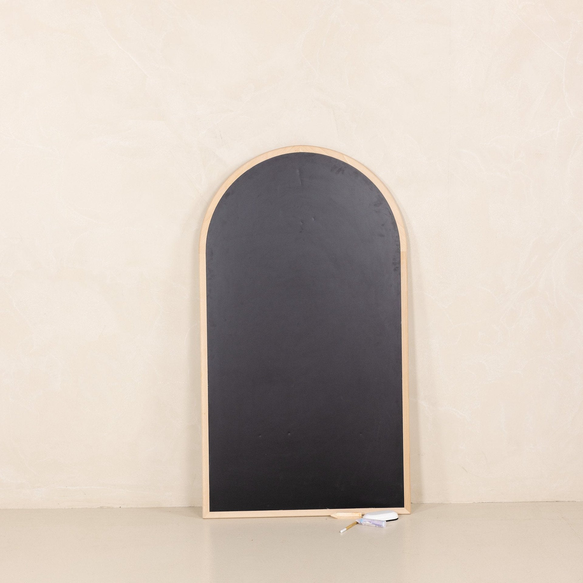 Arched blackboard with wooden frame on a beige background