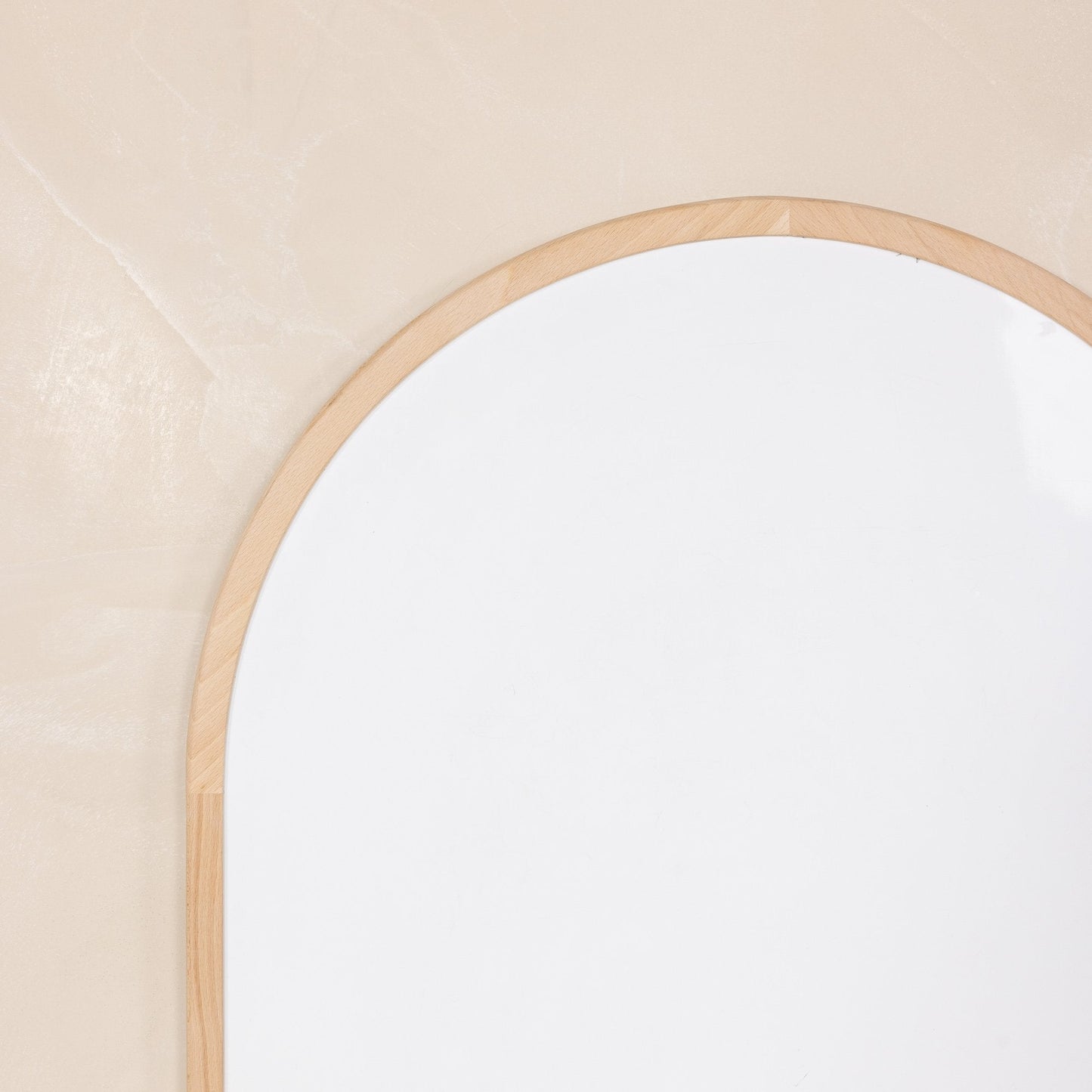 Round mirror with a wooden frame on a beige wall