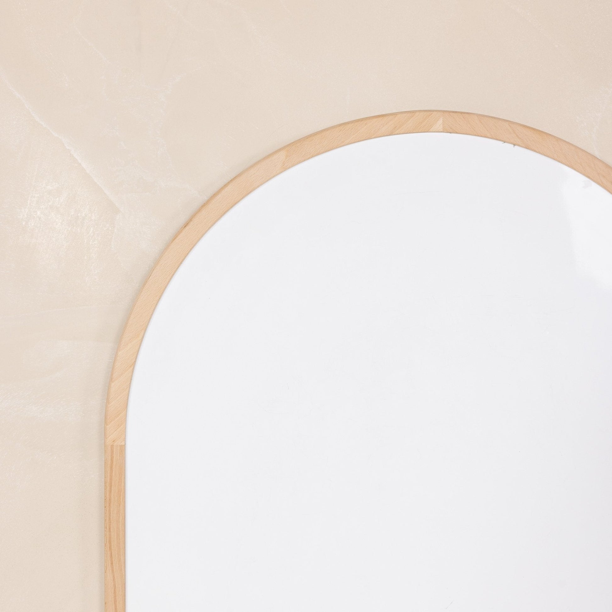 Round mirror with a wooden frame on a beige wall