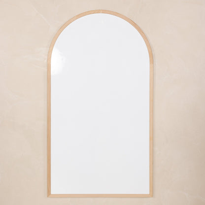 Arched mirror with a wooden frame on a beige wall
