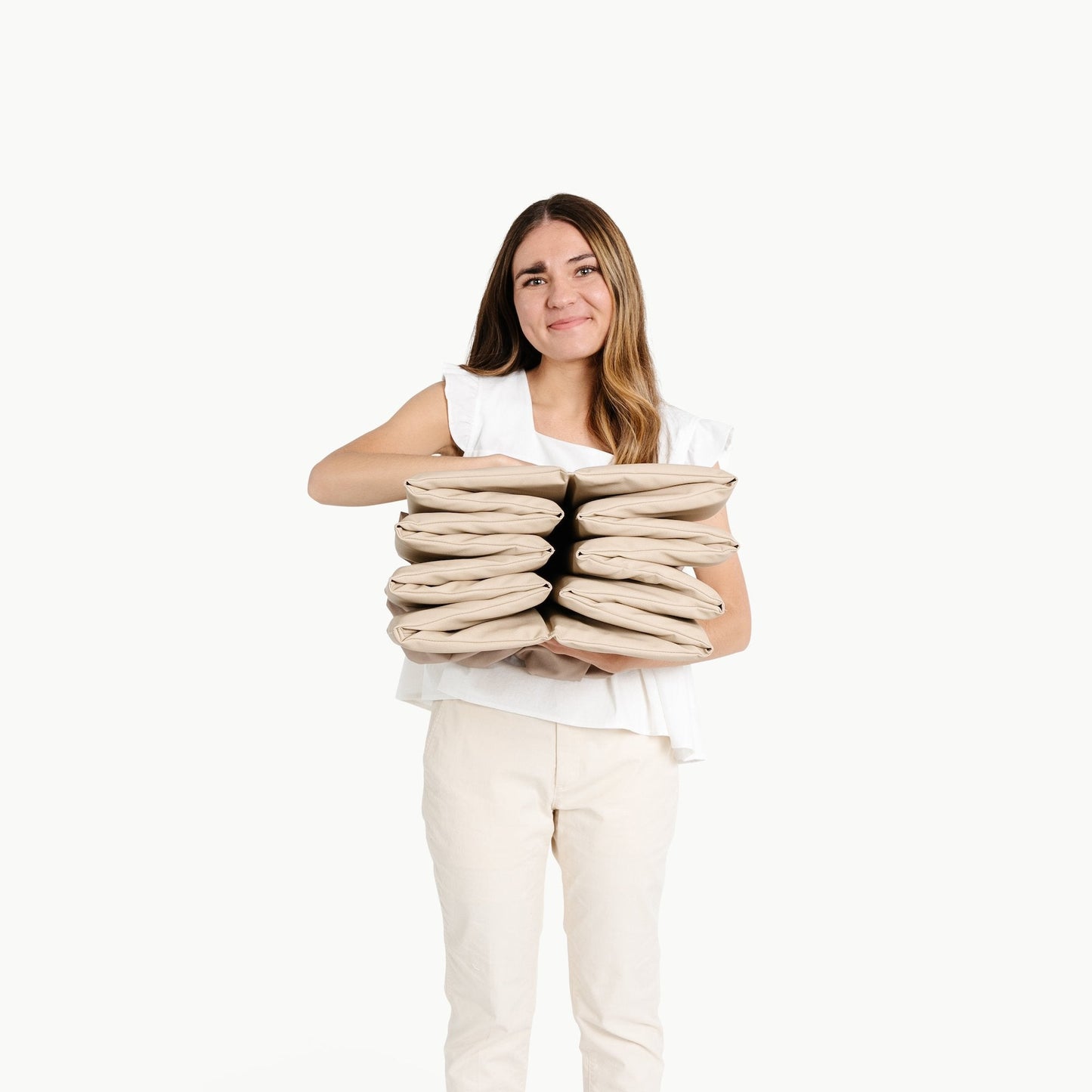 Woman holding a stack of pillows against a white background
