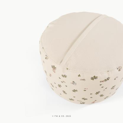 Round beige cushion with floral pattern on a white background