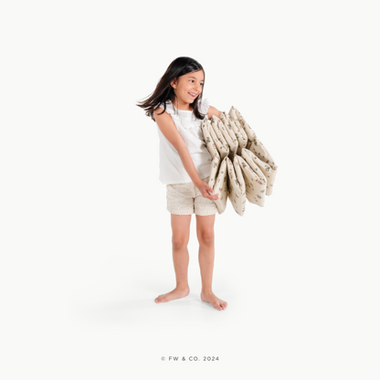 Young girl holding a stack of folded towels on a white background
