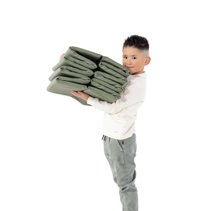 Child holding a stack of green blankets on a white background